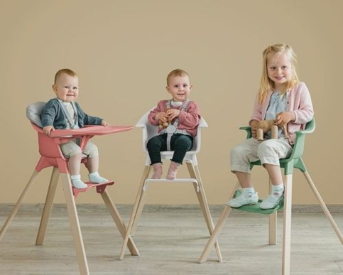 Trona Stokke Clikk en uso con el reposapi&eacute;s ajustable mostrando a beb&eacute;s de diferentes edades